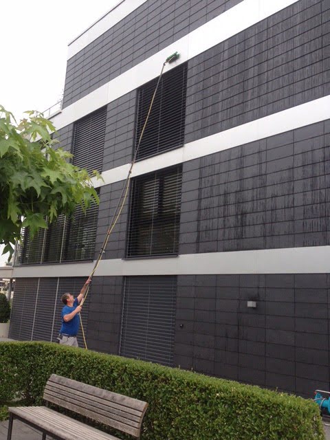An employee cleaning a facade on a building in Zug